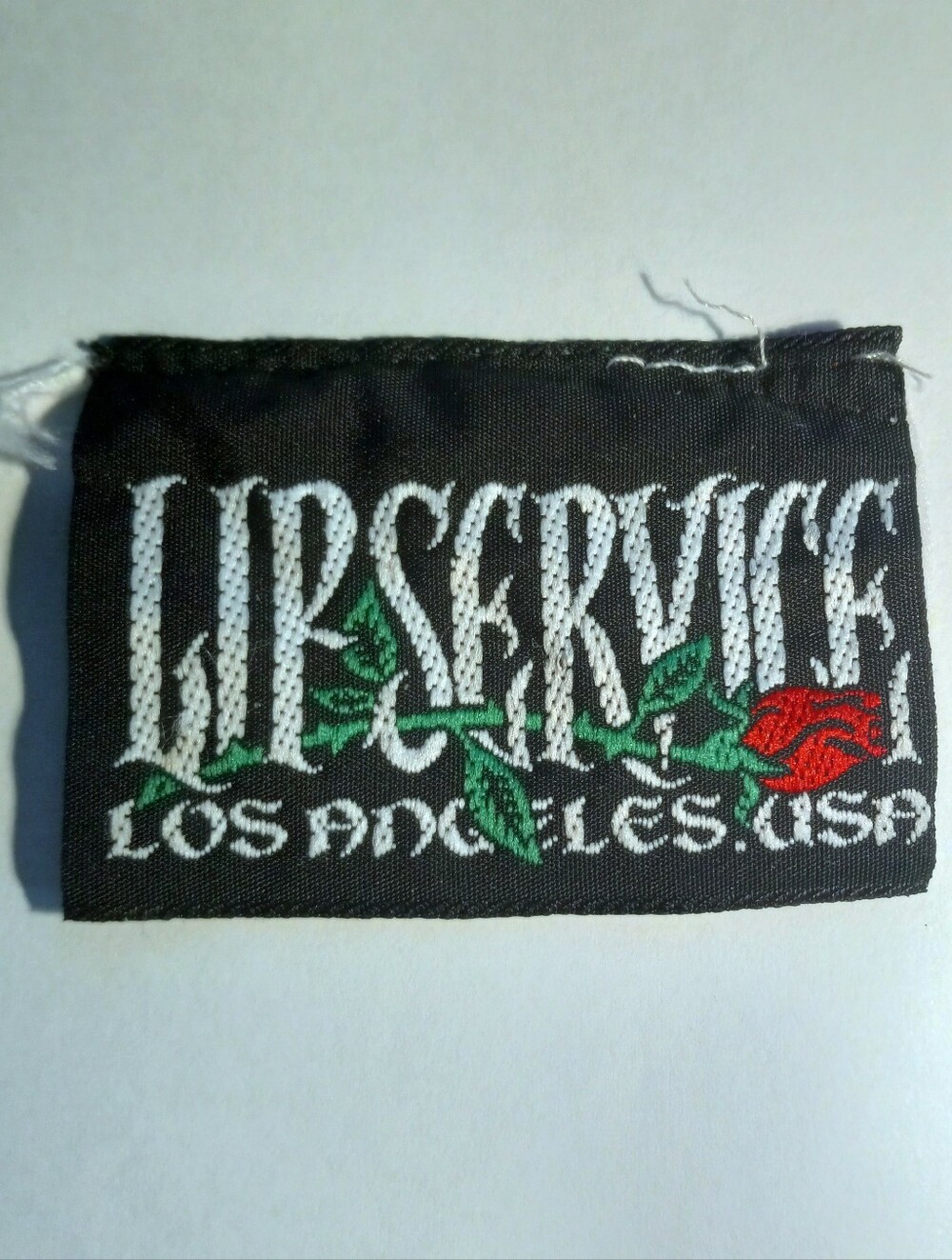 Lip Service Black Tag with White Lettering and Red Rose